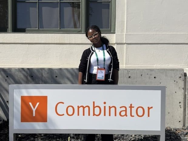 Tobi standing behind the Y Combinator sign outside its building, wearing an event badge.